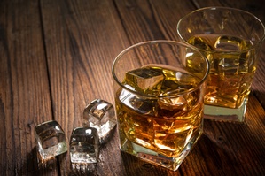 Glasses of whiskey with ice on wooden table